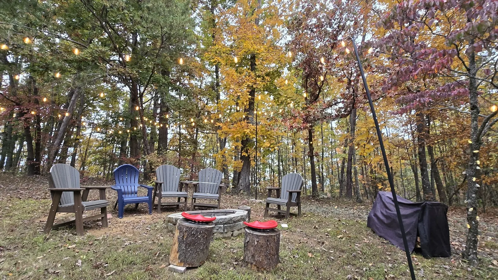 Fire pit seating beneath fall foliage and string lights at Peaceful Ridge