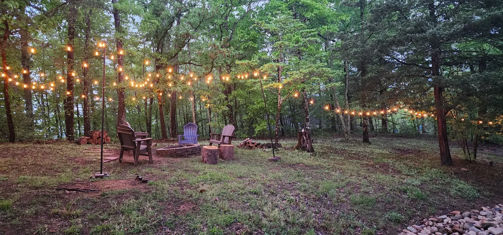 Large wooded outdoor gathering area with café lights at Peaceful Ridge